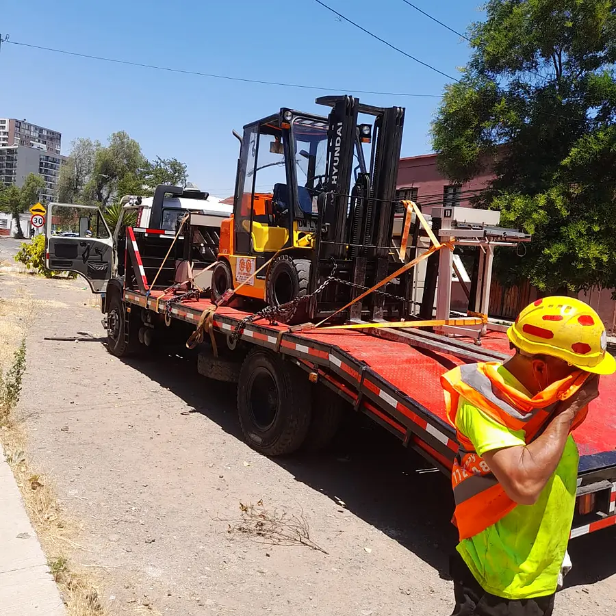Rigger de Grúas Sotomayor junto al camión cama baja cargado con maquinaria