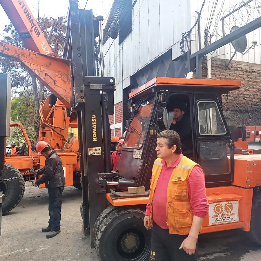 Operador y riggers coordinando el izaje de una máquina con grúa pluma